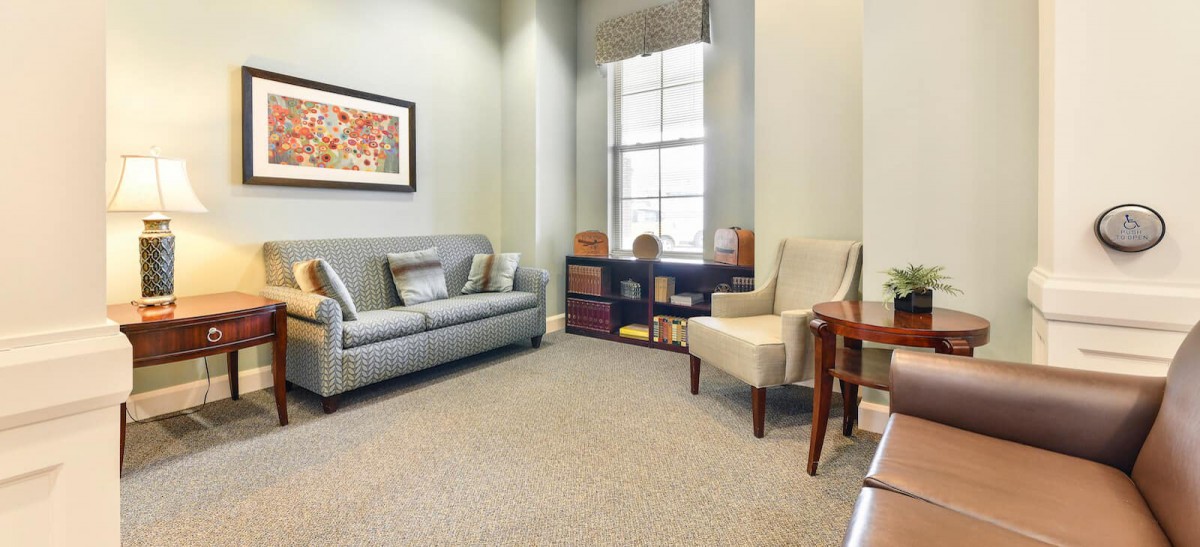 A cozy living room with a sofa, chair, and artwork on the wall.