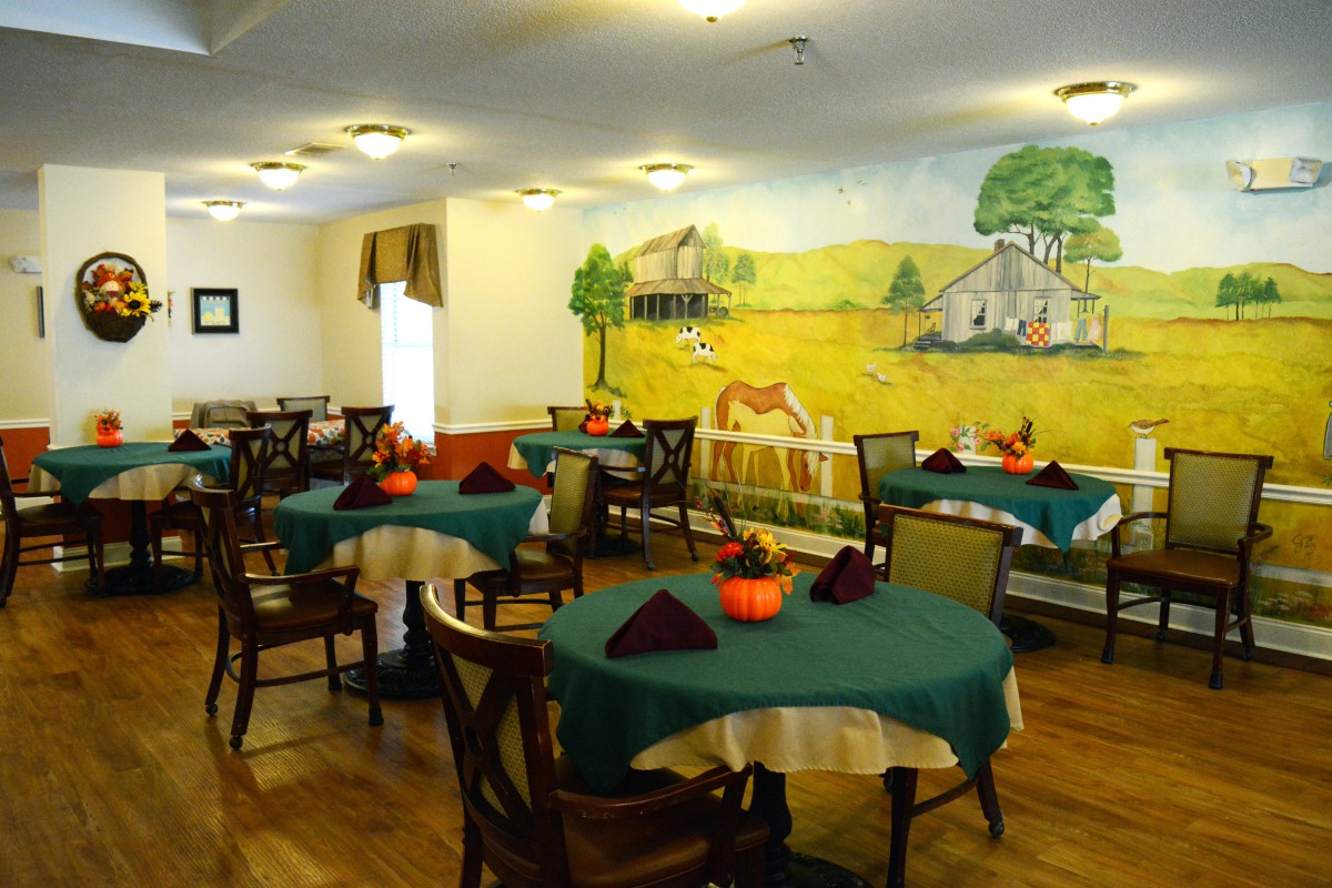 A cozy dining room with tables and chairs, featuring a colorful farm-themed mural on the wall.