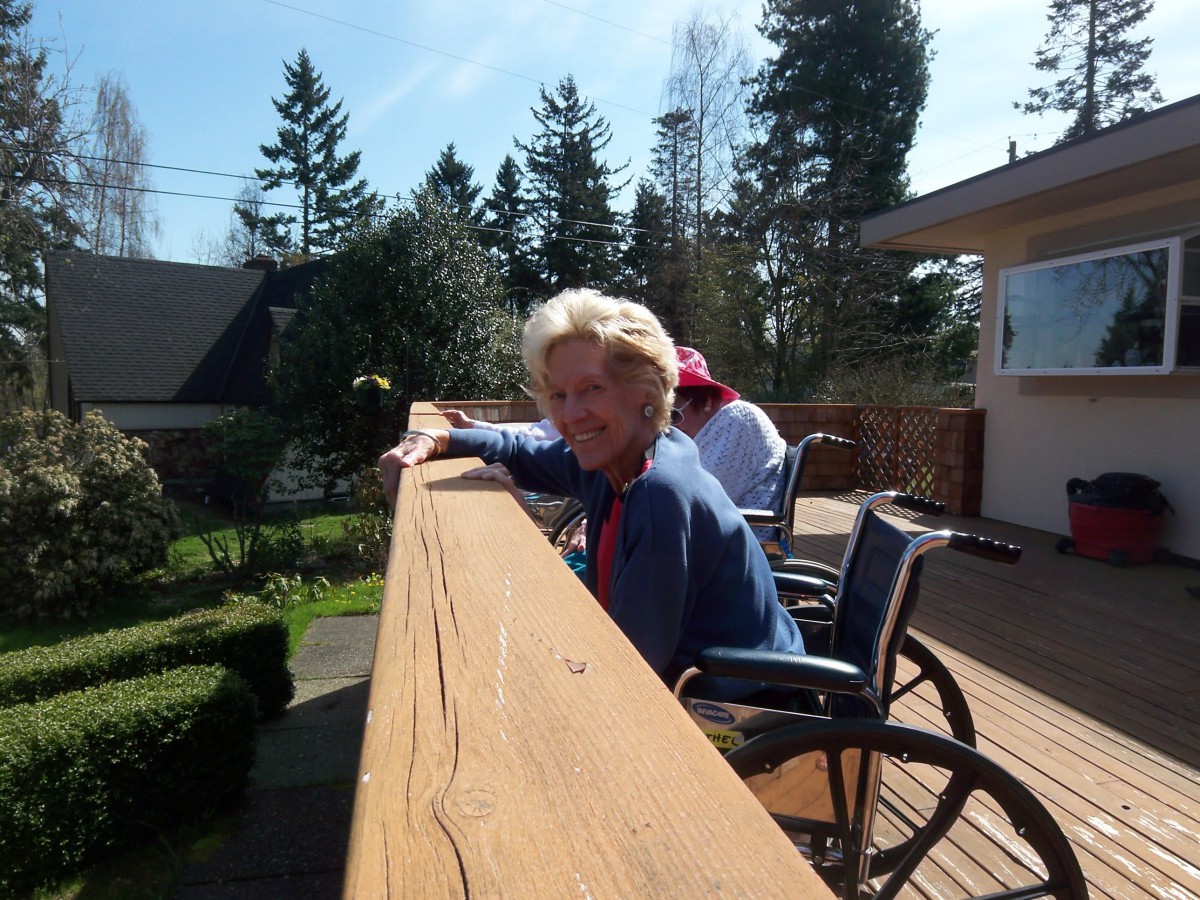 People enjoying a sunny day on the deck in wheelchairs.