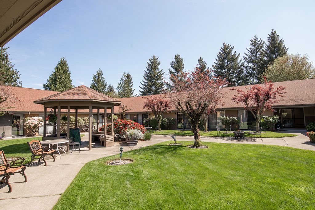 A serene outdoor garden with a gazebo and lush green lawn.