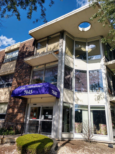 A modern apartment building featuring large windows and a purple canopy.