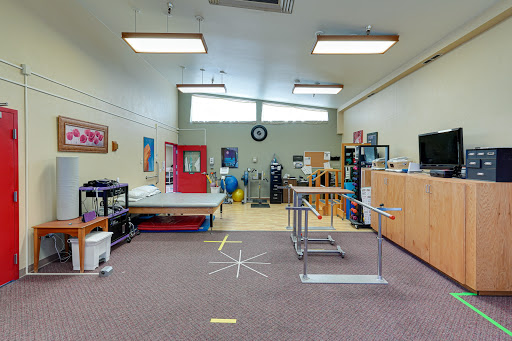A spacious therapy room equipped with various rehabilitation tools and resources.