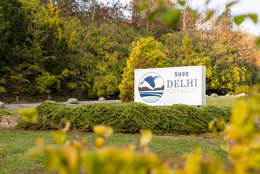 A welcoming sign for Delhi surrounded by lush greenery.