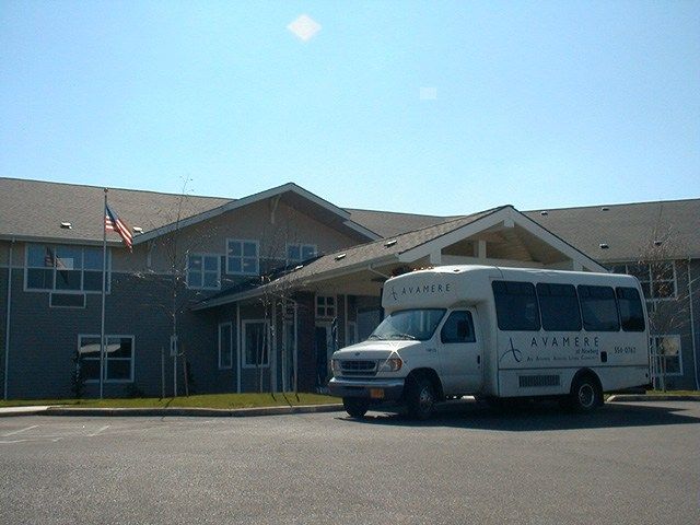 A van parked in front of a building under a clear blue sky.