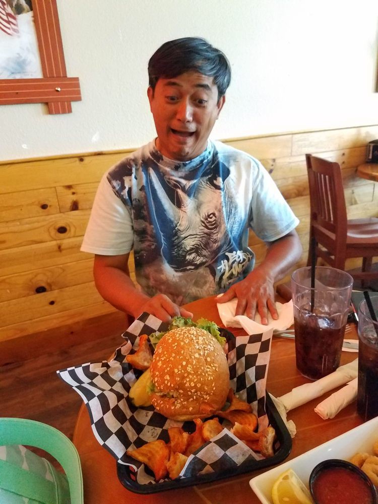 A person excitedly looks at a large burger in a restaurant.
