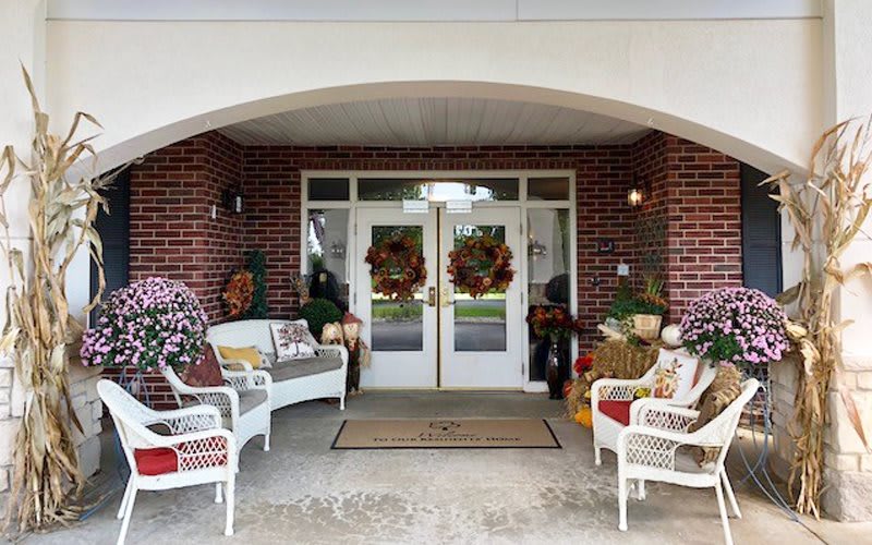 A welcoming front porch decorated for fall with wreaths and cozy seating.