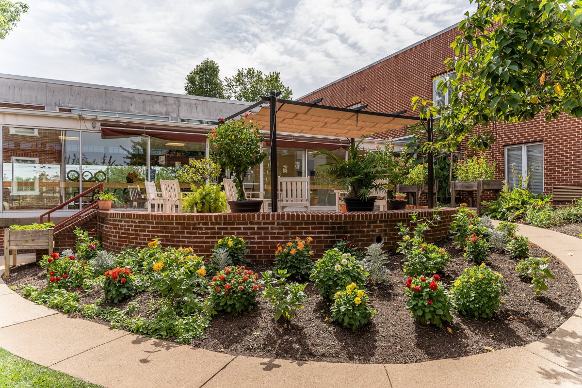 A beautifully landscaped garden with a patio and pergola surrounded by vibrant flowers.