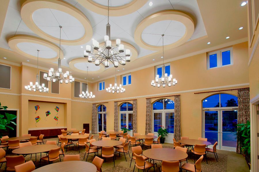 Elegant dining hall with round tables, chairs, and chandeliers.