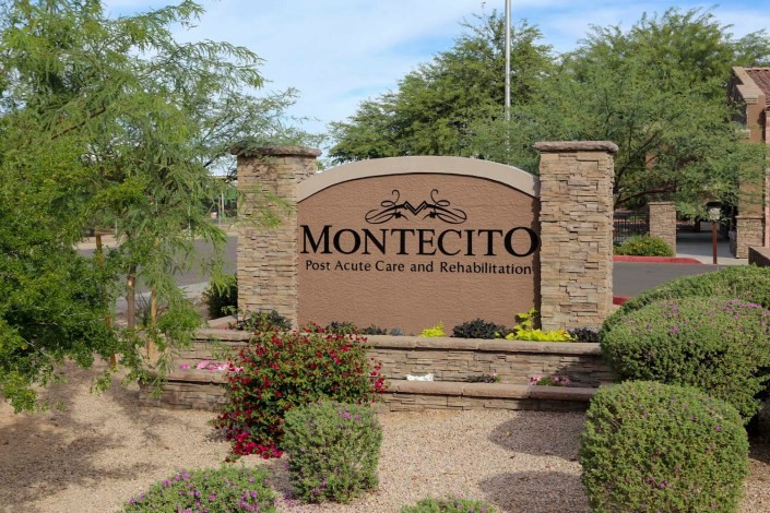 Entrance sign for Montecito, surrounded by plants and stone pillars.
