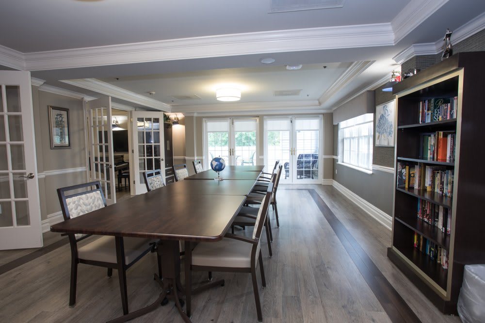 A modern conference room with a long table and several chairs, well-lit by natural light from large windows.