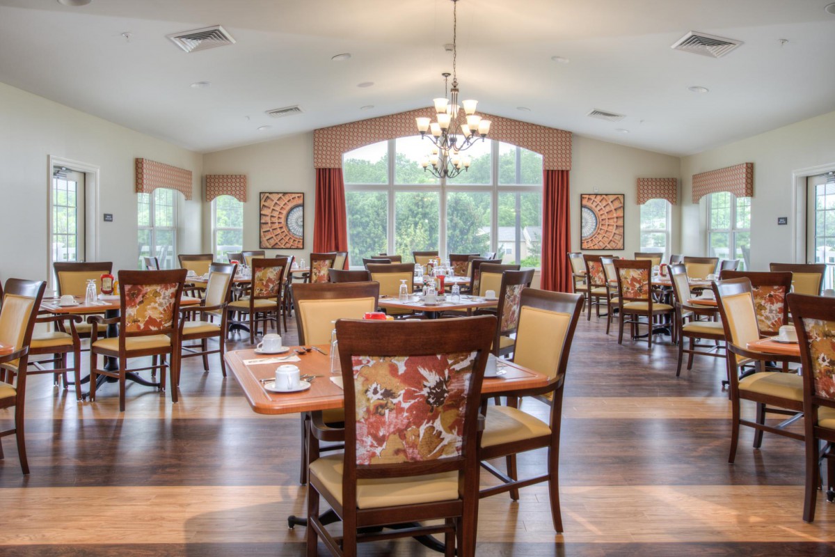 A spacious and elegantly designed dining room featuring multiple tables and chairs, with large windows allowing natural light to fill the space.