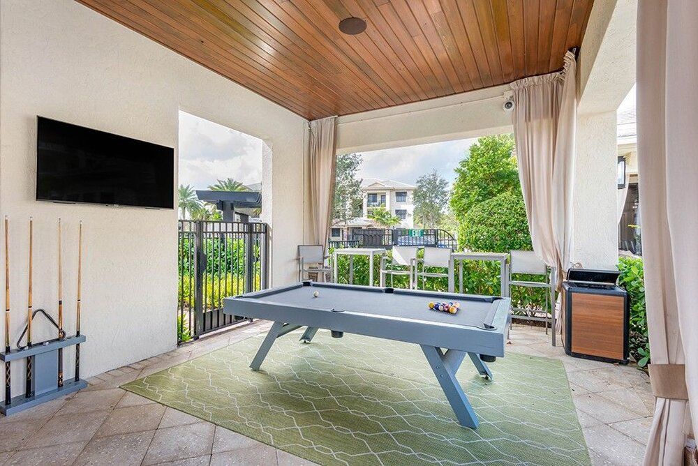 An outdoor recreation space featuring a pool table, television, and a garden view.