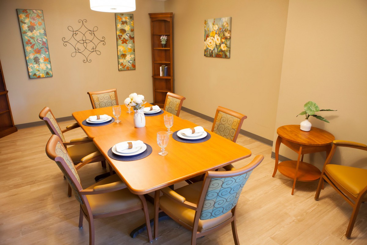 A neatly arranged dining room with a wooden table set for a meal.