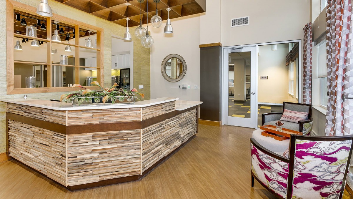 A modern reception area featuring a wooden desk, stylish lighting, and a comfortable waiting space.