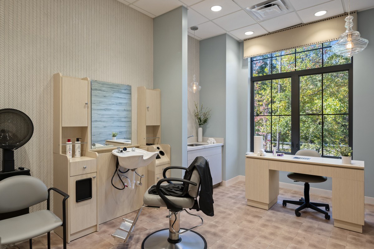 A modern hair salon interior with styling chair and large window.