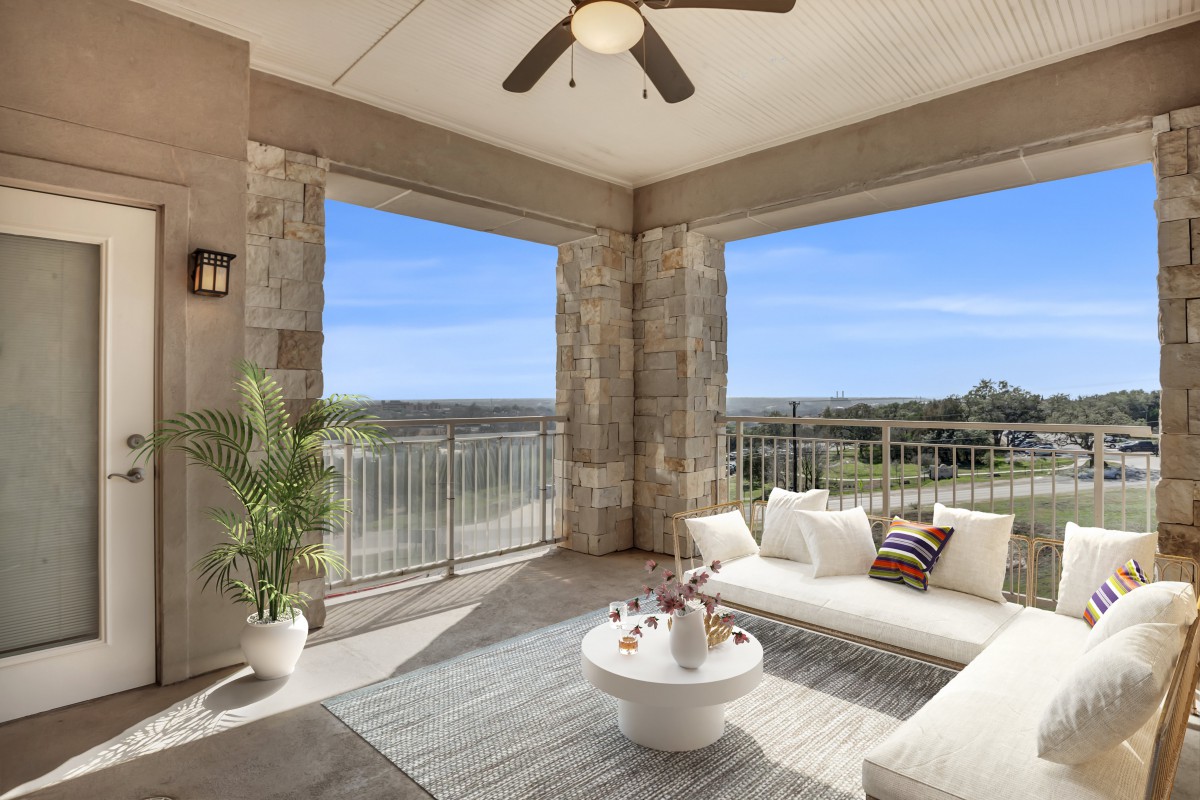 A stylish outdoor patio with comfortable seating, a ceiling fan, and a scenic view.