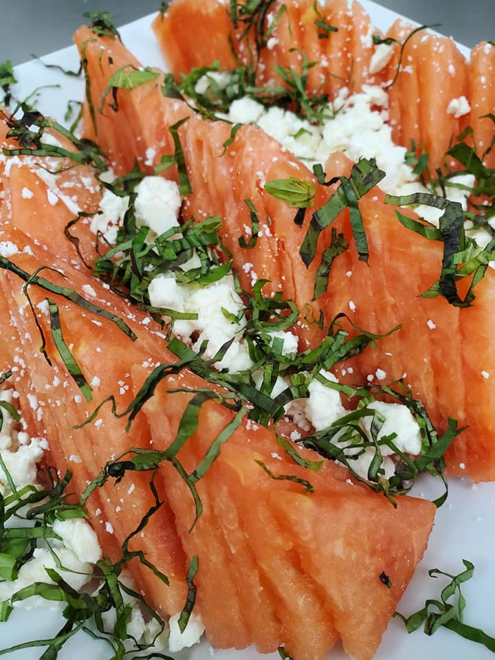 A refreshing watermelon salad topped with feta cheese and fresh herbs.
