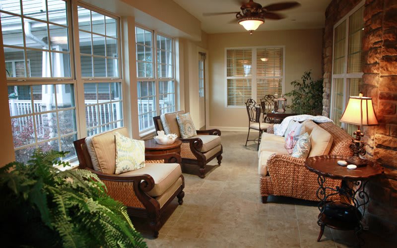 A cozy sunroom with comfortable seating and large windows, allowing natural light to fill the space.