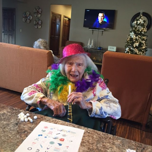 An elderly woman enjoying a festive celebration with colorful attire and accessories.
