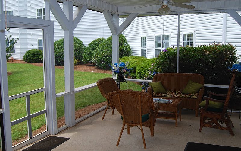 A cozy covered porch with wicker chairs and a garden view.
