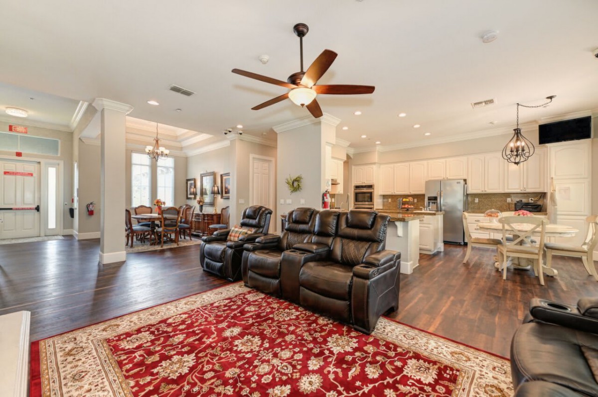 Spacious open living area with leather seating, a ceiling fan, and an adjoining kitchen and dining space.