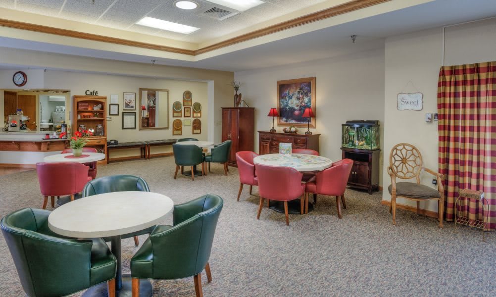 A cozy lounge area featuring tables with colorful chairs, an aquarium, and various artwork on the walls.