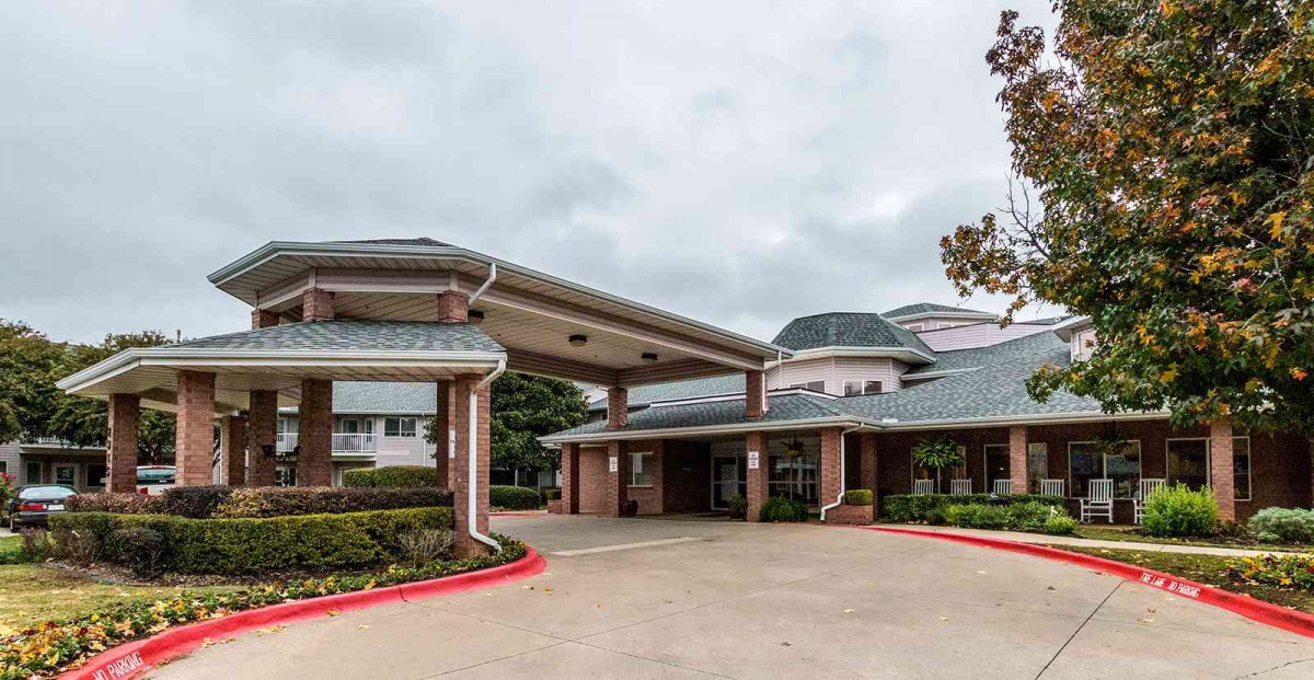 A building with a covered entrance and a driveway in front.