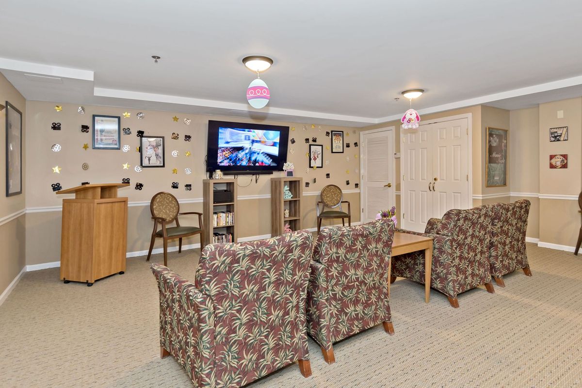 A cozy living room setting with patterned chairs, a mounted television, and various wall decorations.