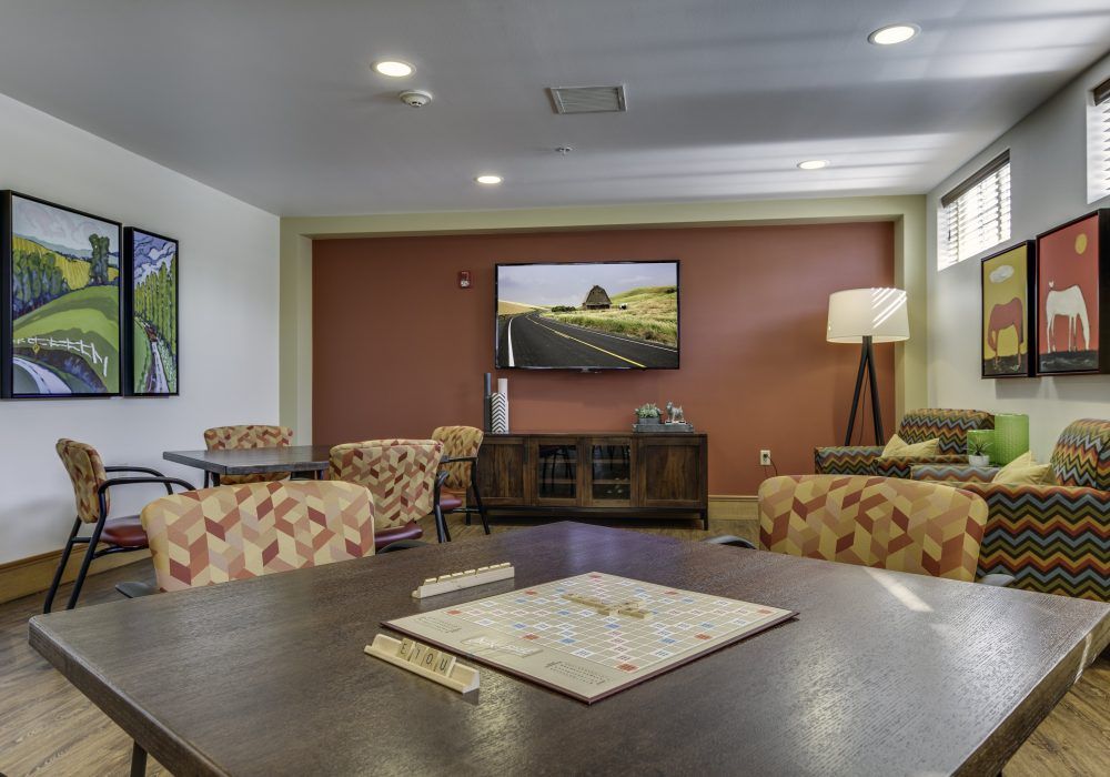 A cozy living room with comfortable seating and a television on the wall.