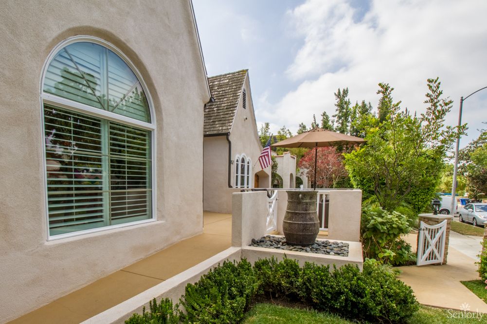 A beautifully landscaped garden area with a patio and decorative vase next to a house.