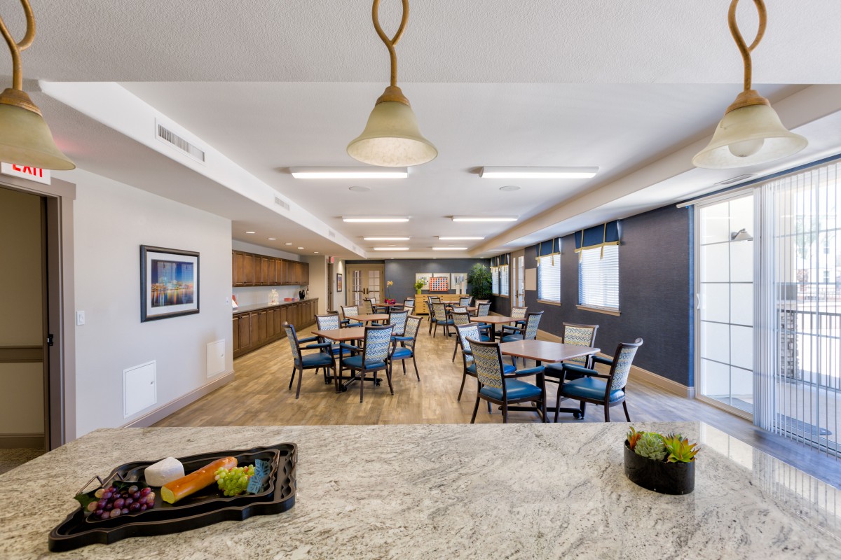 A modern dining space with multiple tables and chairs, complemented by contemporary lighting and kitchen facilities.