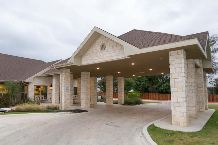 A building entrance with covered driveway and columns.