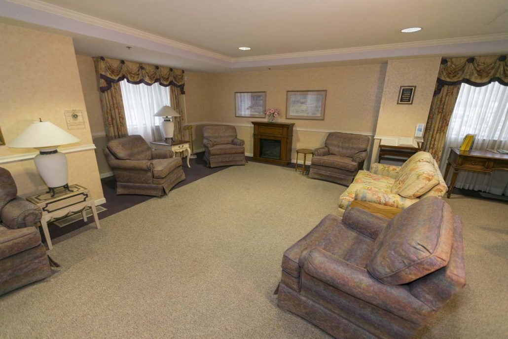 A cozy living room with several sofas and chairs arranged around a central fireplace.