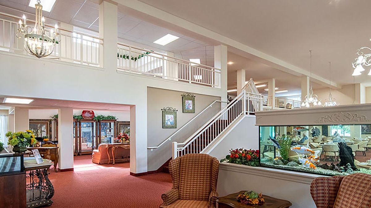 A spacious lobby area featuring a staircase, seating, and an aquarium.