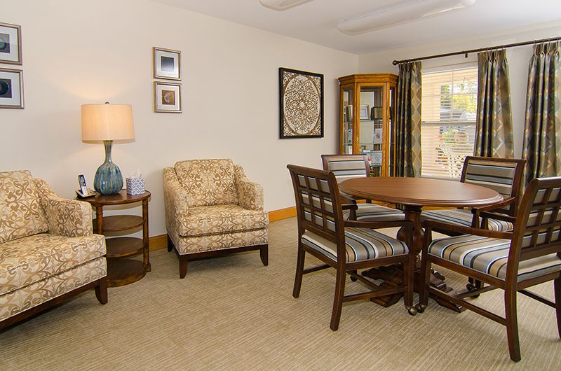 A cozy living room with a round dining table, armchair, and elegant decor.