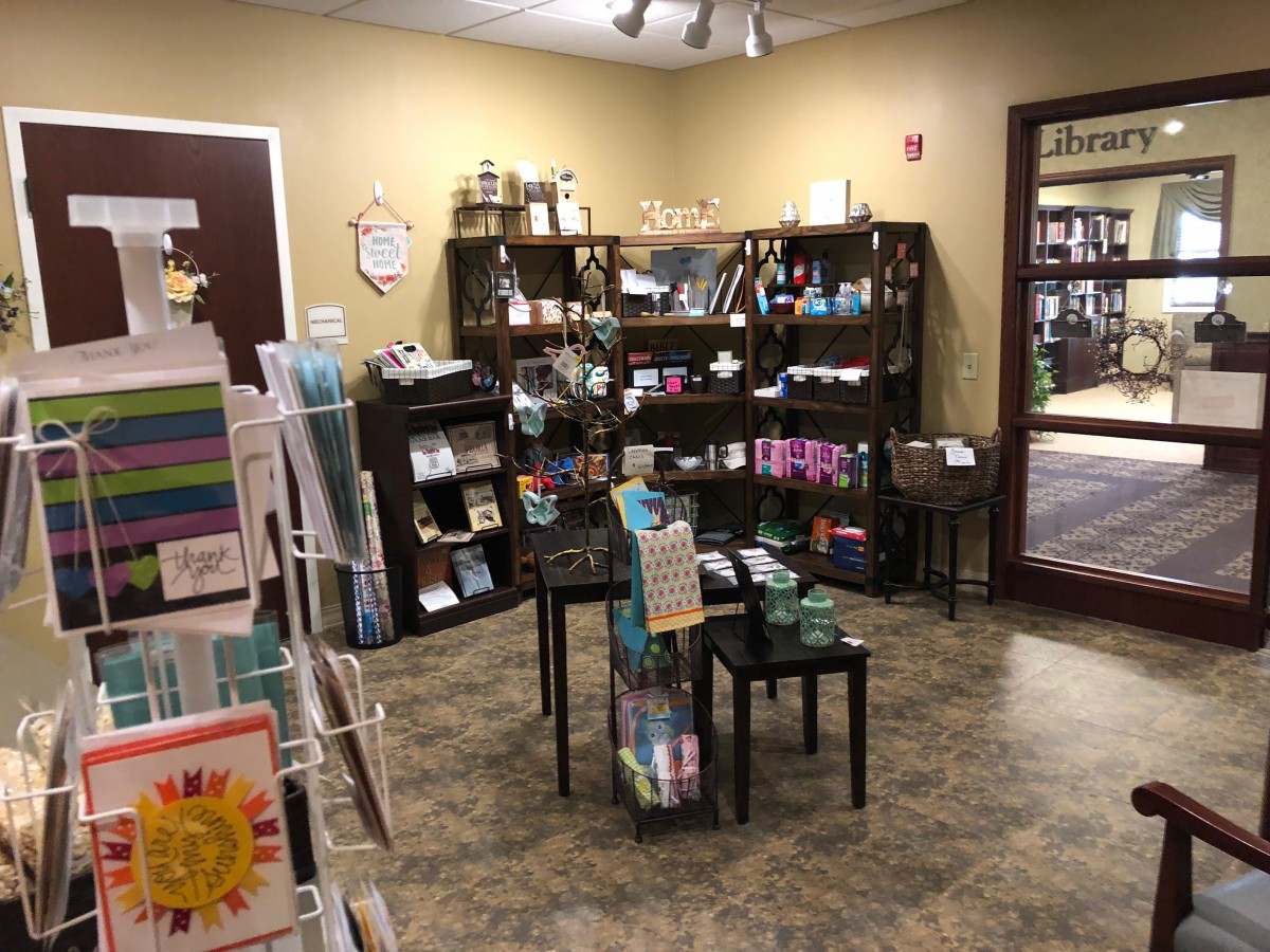 A cozy store interior featuring shelves stocked with a variety of wellness products and greeting cards.