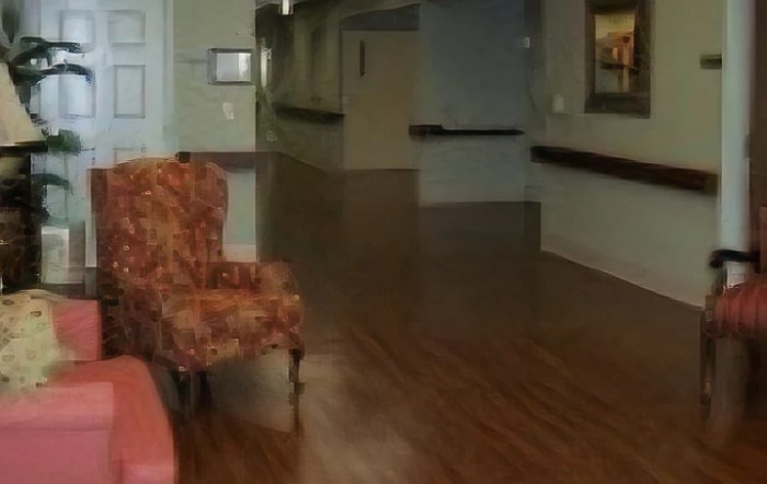 A quiet hallway with a patterned armchair and wooden flooring.