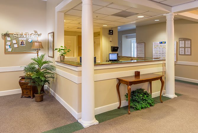 A welcoming reception area featuring a desk, potted plants, and classic decor.