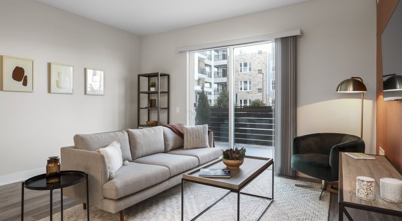 A modern living room with a comfortable sofa, coffee table, and large window overlooking an urban setting.