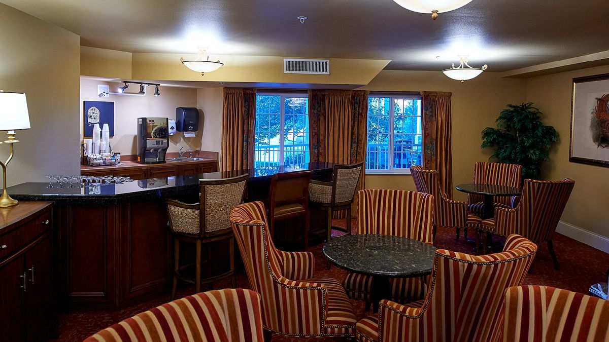 A cozy lounge area with striped chairs and a bar counter, featuring large windows.