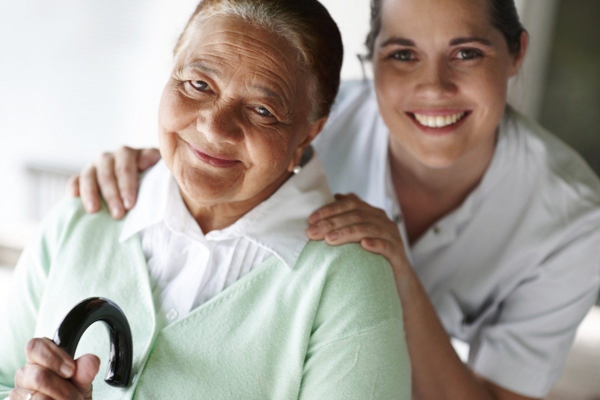 An elderly woman and a young woman smiling, showing care and support.