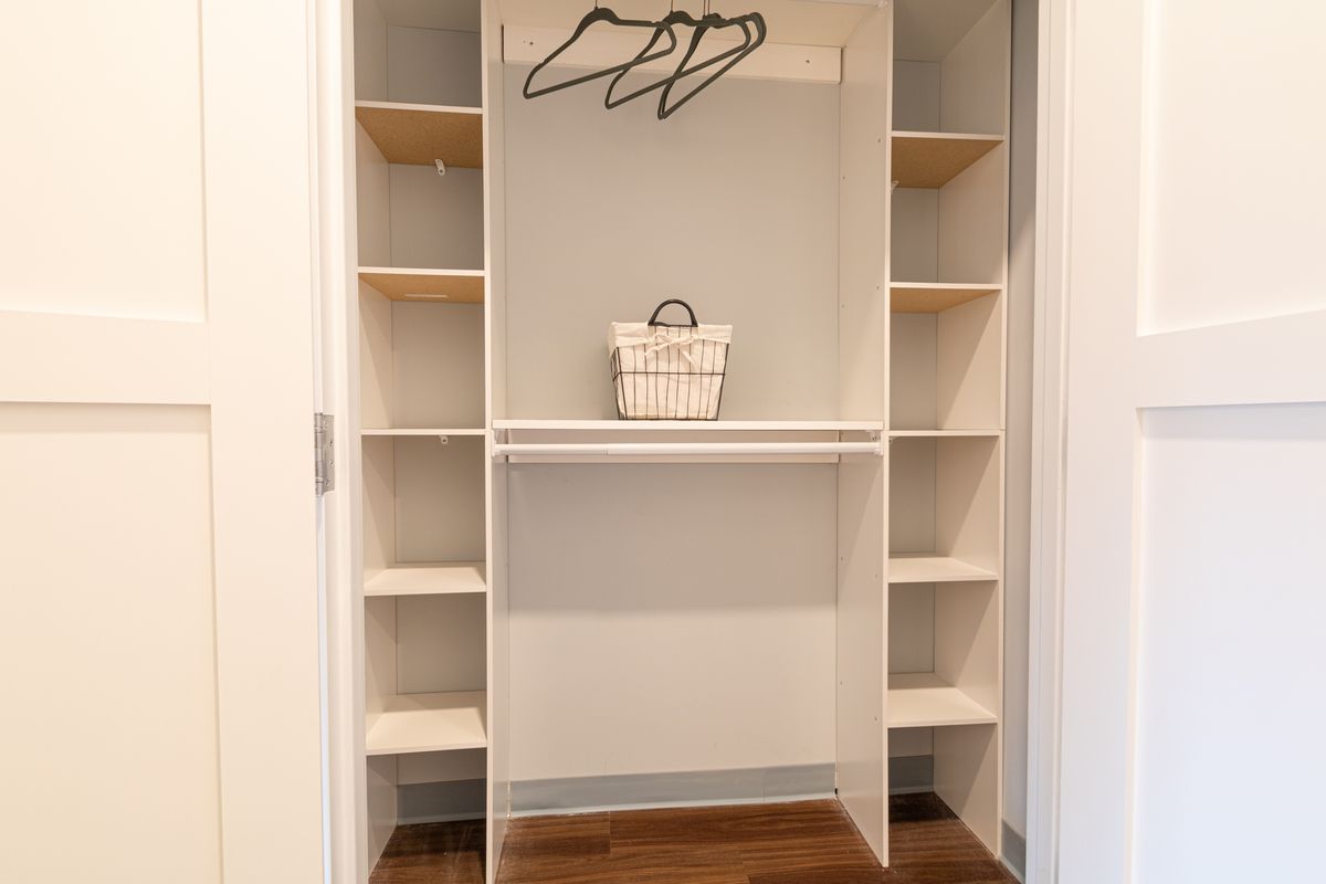An organized closet with shelves, hangers, and a small basket.