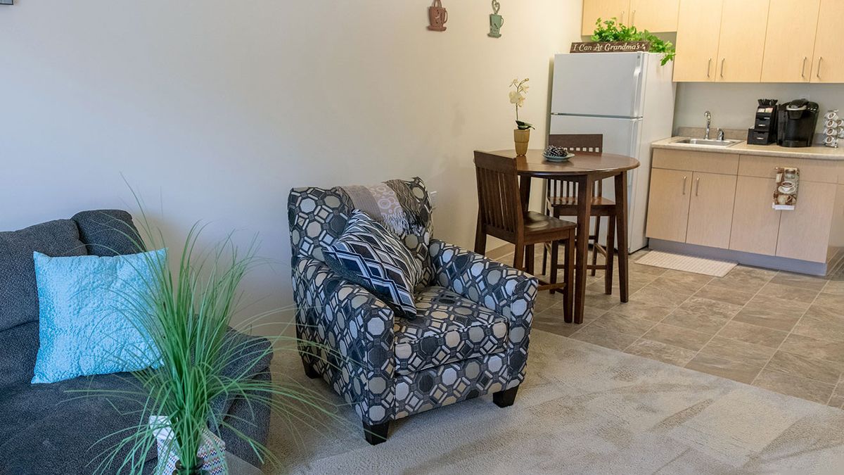 Cozy living and dining area with a patterned armchair and indoor plants.