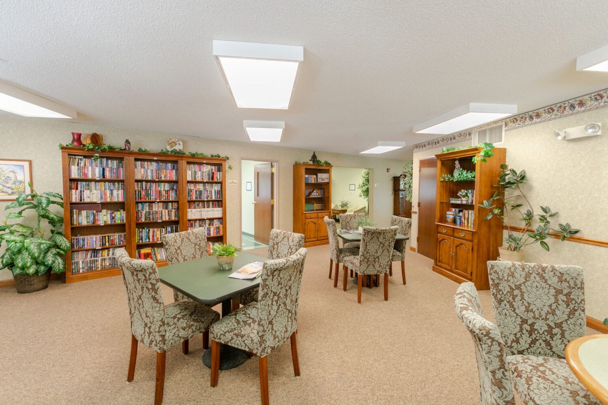 A cozy library room with bookshelves, tables, and chairs for reading.
