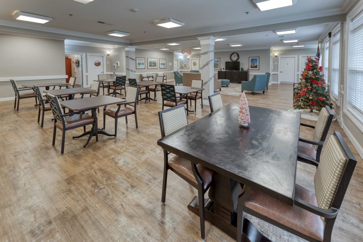 A spacious dining area with several tables and chairs, featuring a wooden floor and modern decor.
