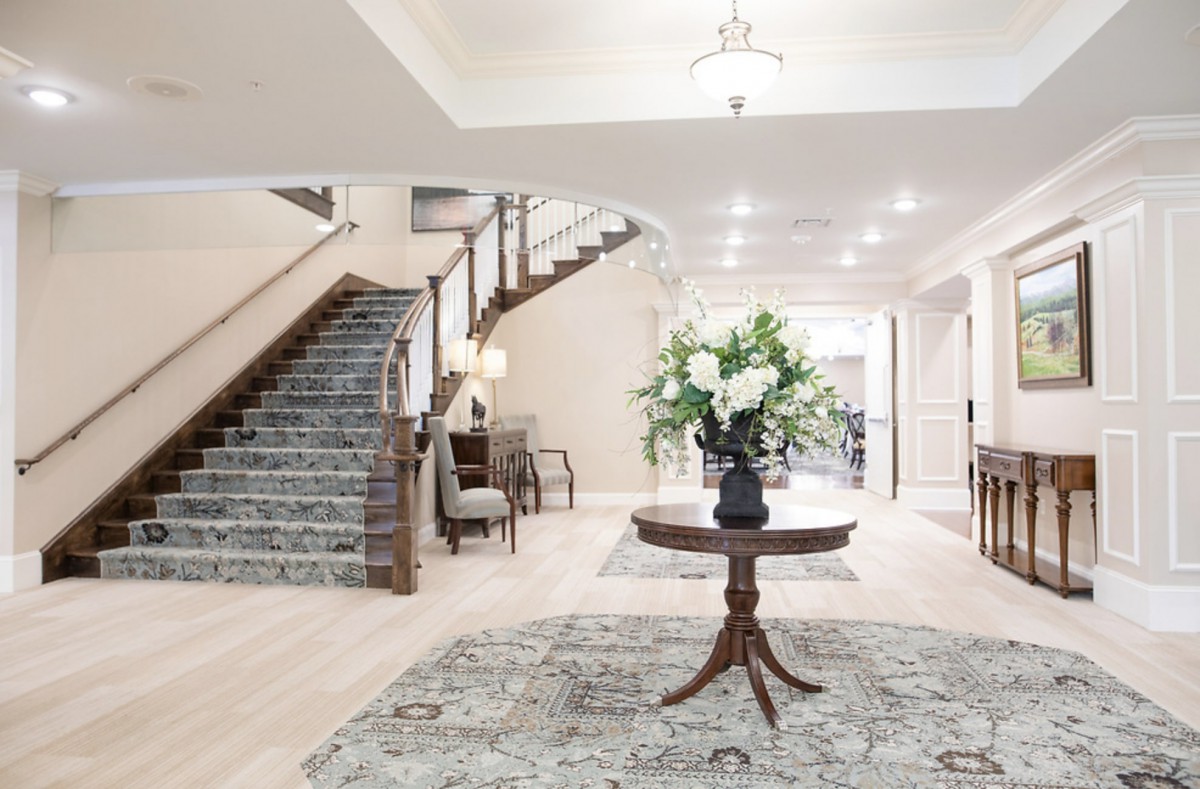 Elegant foyer with a central table adorned with flowers and a grand staircase.