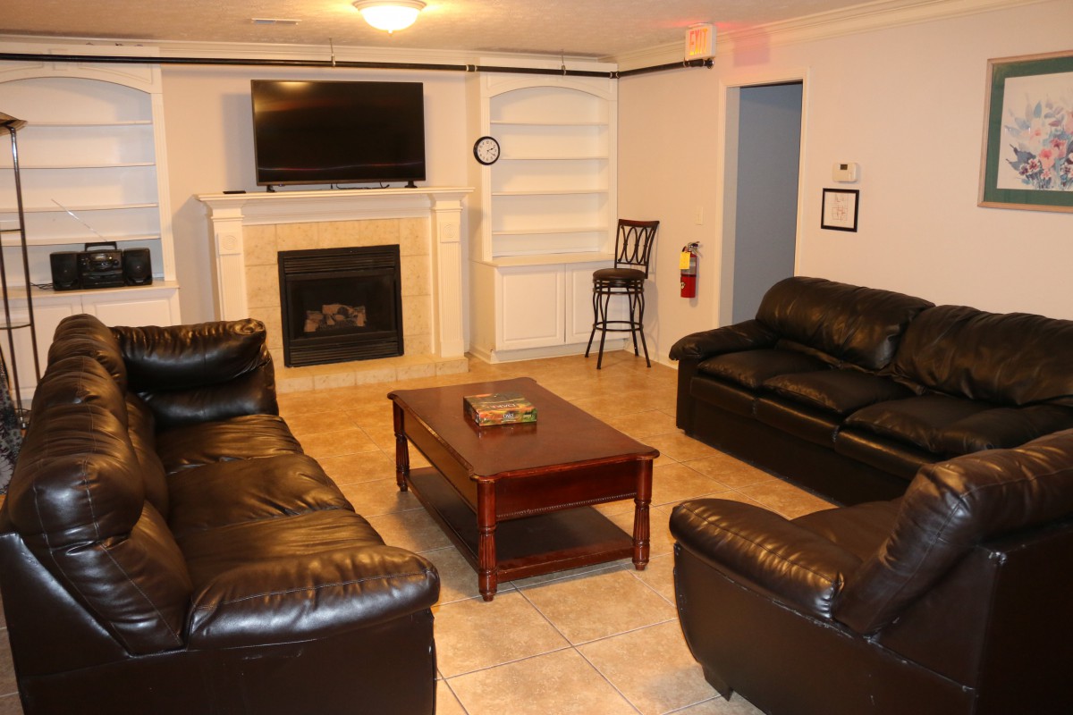 Cozy living room with leather sofas, a fireplace, and a wall-mounted television.