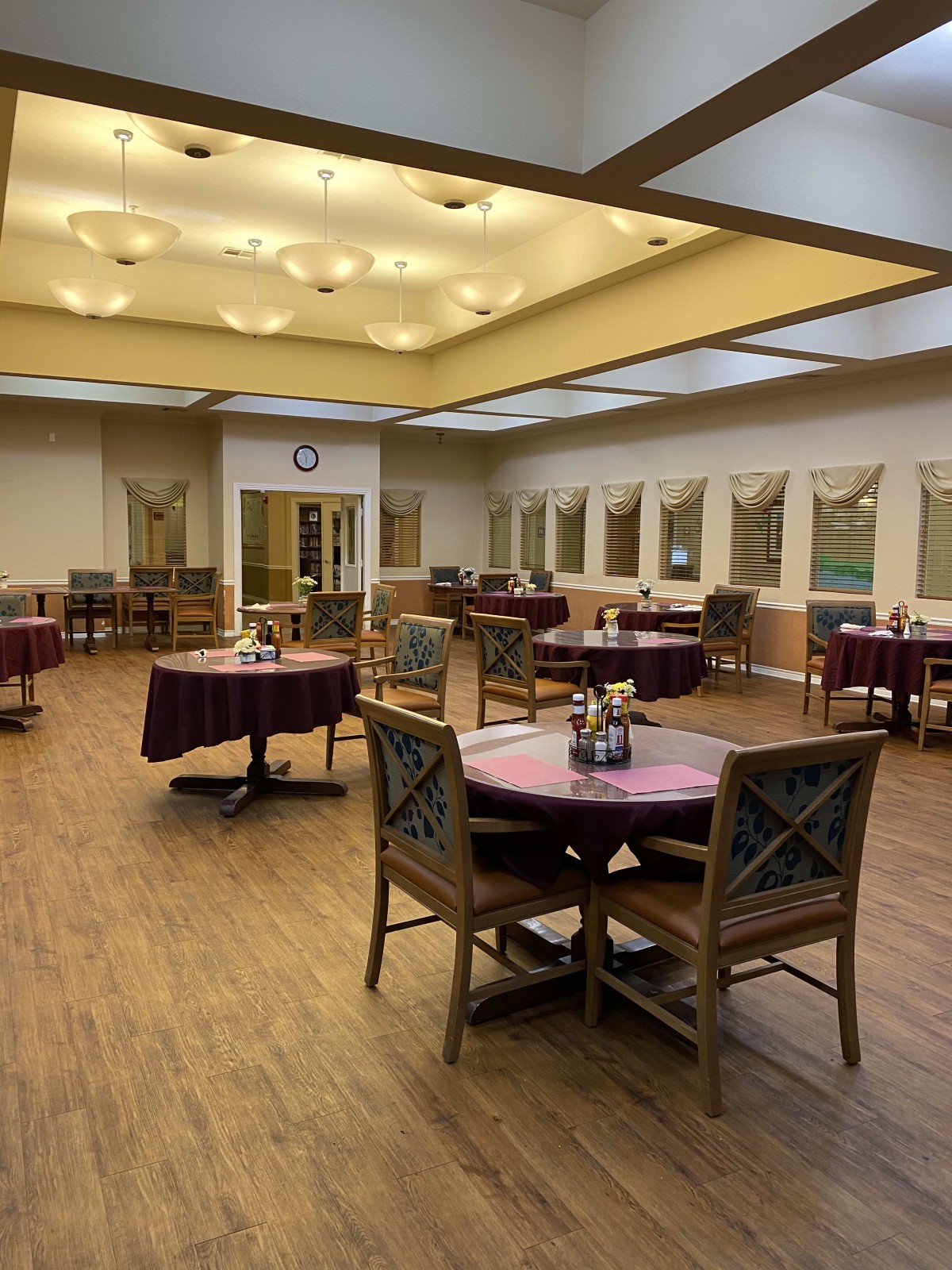 An empty dining area with neatly arranged tables and chairs under warm lighting.