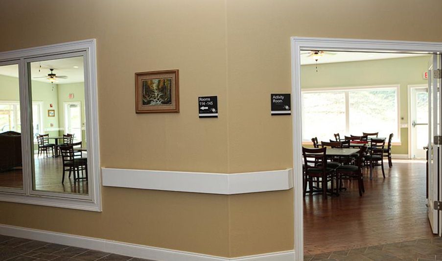 A hallway with a view into a dining room, featuring wall signage and a framed painting.