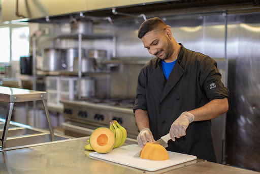 A chef skillfully slicing a cantaloupe in a modern kitchen.